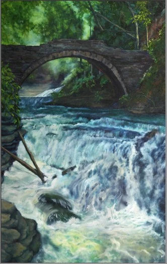 White water rushes over rocks beneath a stone bridge surrounded by green trees.