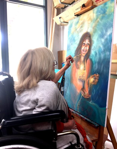 Joyce Huntington at her easel, painting in her studio.